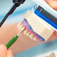 Incamol odontólogo tallando maqueta de dientes